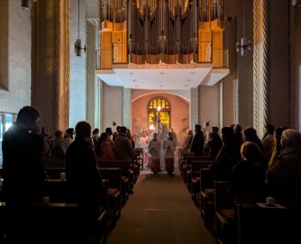 Die osterkerze wird in eine dunkle Kirche getragen