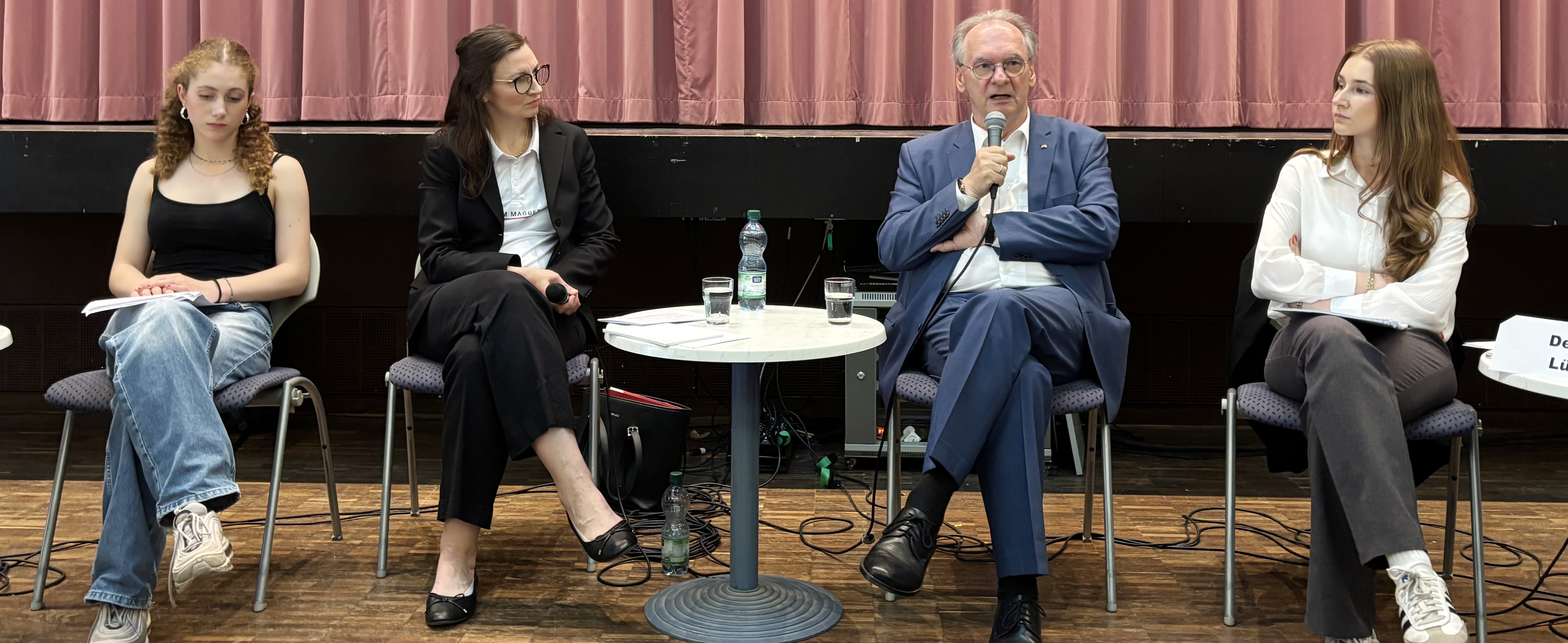 4 Menschen sitzen im Podium und diskutieren.