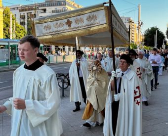 Priester gehen mit einem Baldachin durch eine Stadt