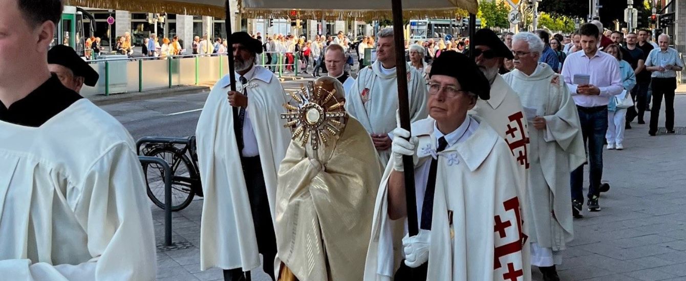 Priester gehen mit einem Baldachin durch eine Stadt