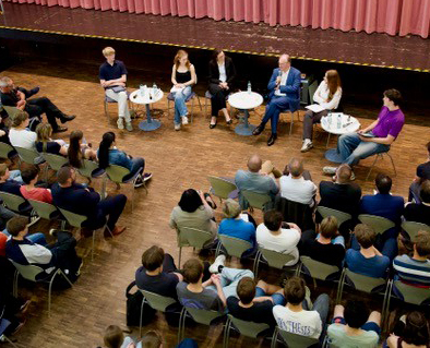 Blick von oben in die Aula der Schule mit Publikum und Podium.