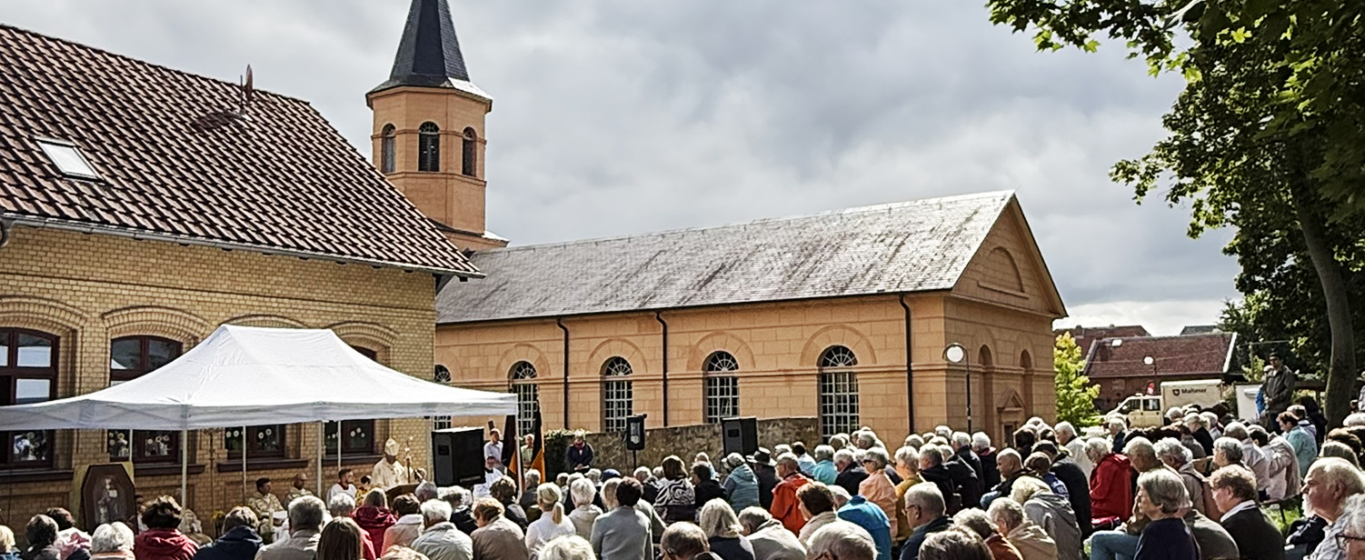 Gläubige auf Banken vor Schinkel-Simultankirche in Haldensleben beim Gottesdienst.
