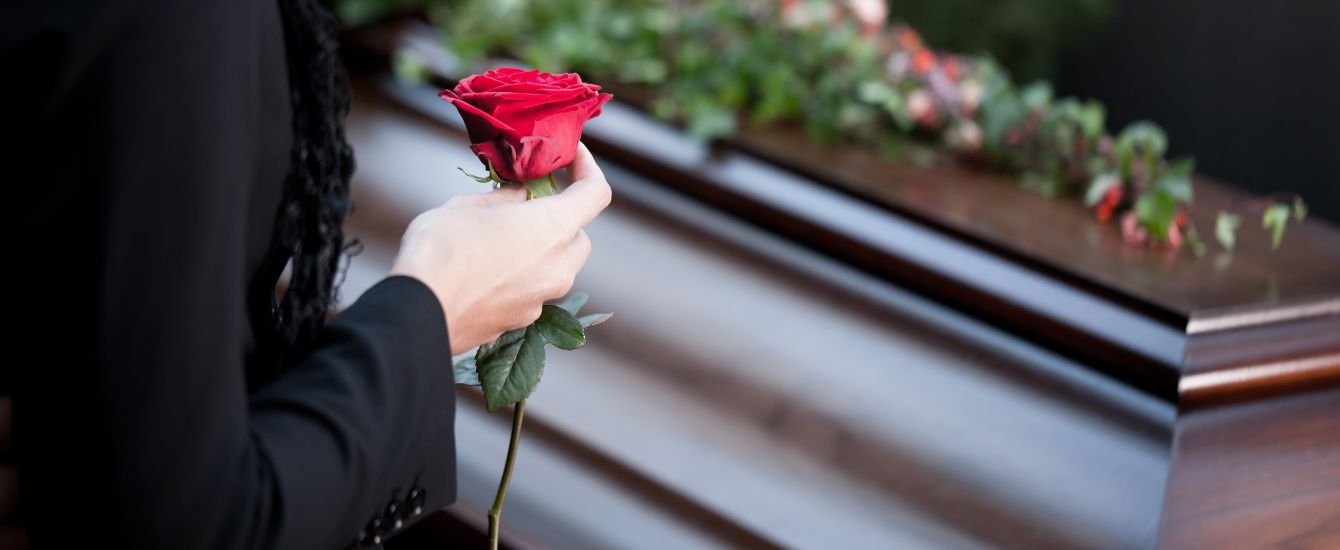 Eine Hand mit Rose vor einem Sarg
