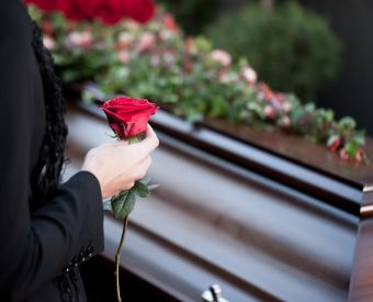 Eine Hand mit Rose vor einem Sarg