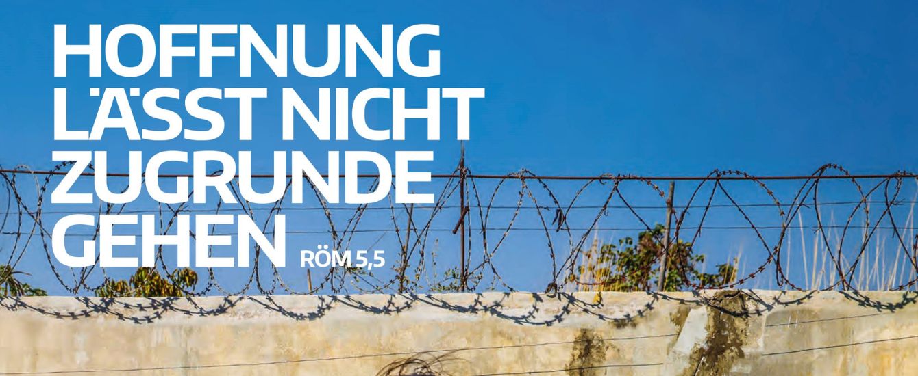 Weiße Schrift, die vor einem Stacheldrahtzaun sagt: Hoffnung lässt nicht zugrunde gehen
