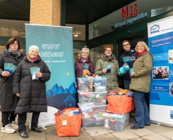 Menschen stehen mit Kisten vor einem Laden