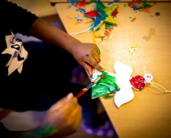 Kinderhände bemalen einen Weihnachtsengel
