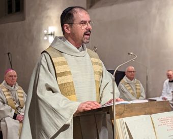 Ein Priester steht am Ambo