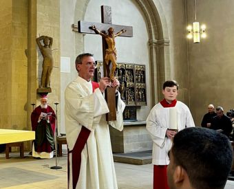 Ein Diakon hält das Kreuz