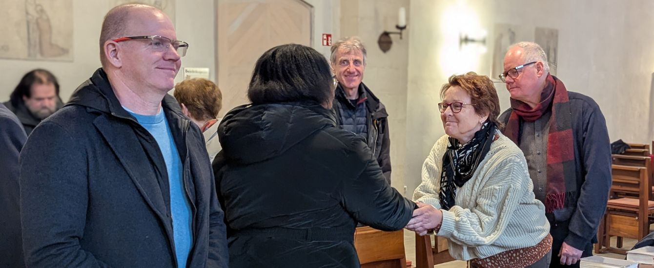 Menschen im Gottesdienst reichen sich die Hände zum Friedensgruß