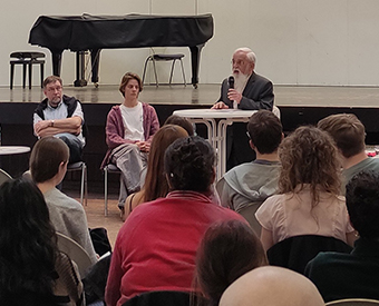 Bischof Feige mit Mikrofon vor Schülerinnen und Schülern