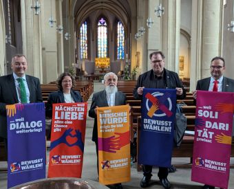 Menschen mit dem Bischof und Bannern in einer Kirche