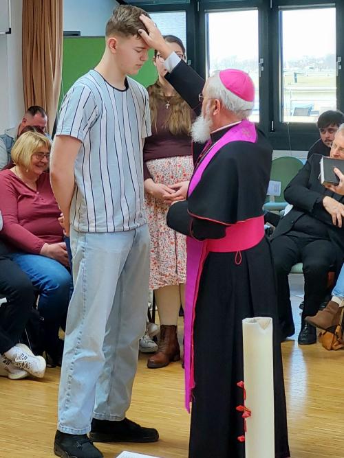 Bischof segnet einen jungen Mann