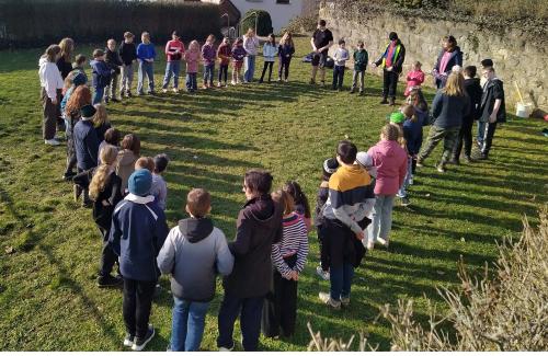 Menschen stehen auf einer Wiese in einem Kreis