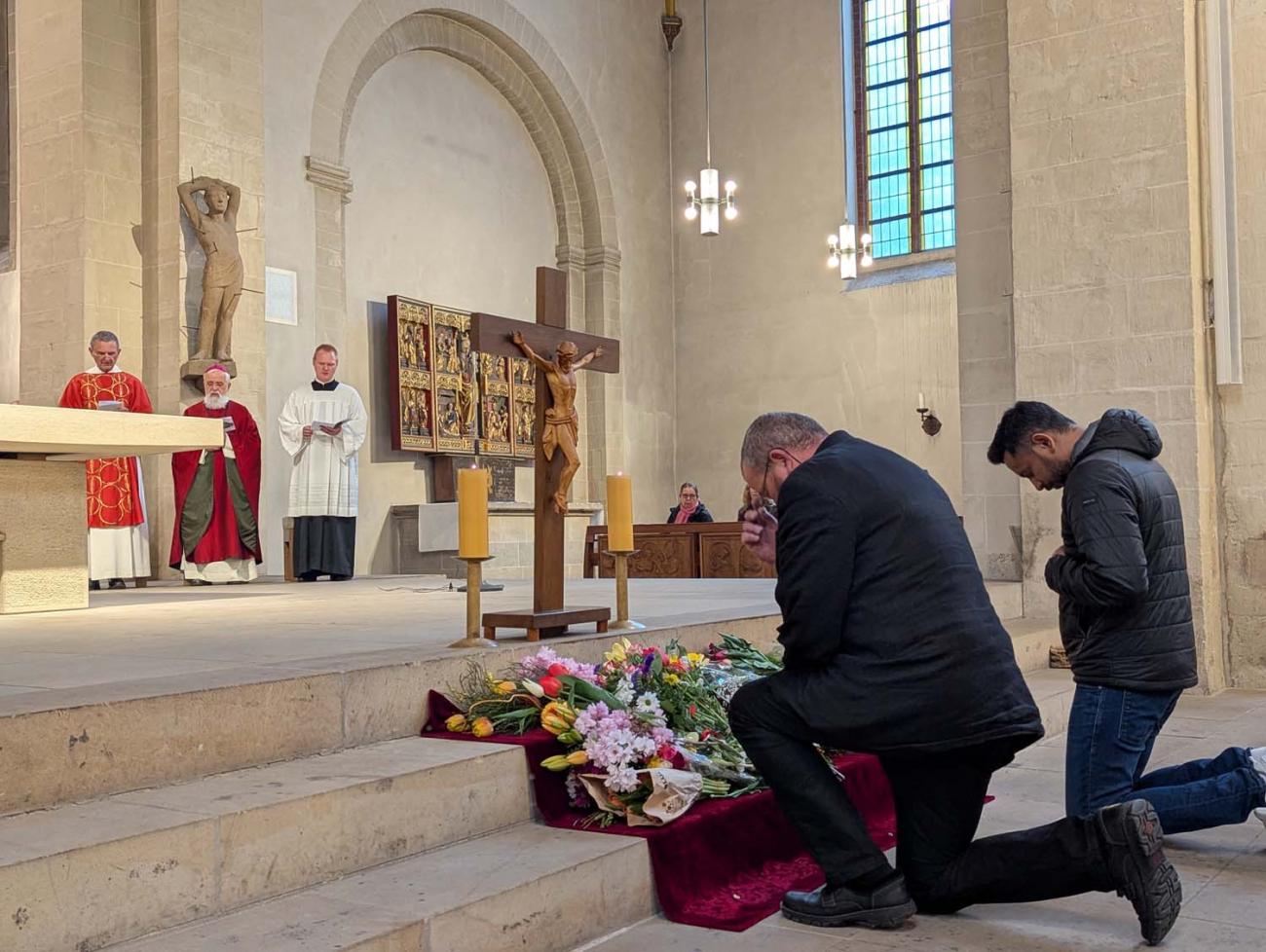 Menschen beten vor einem Kreuz