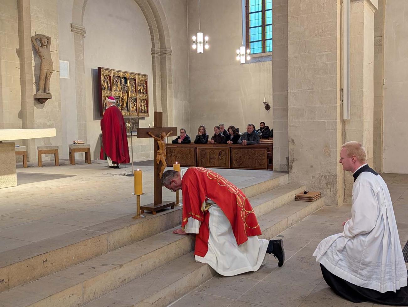 Ein Diakon verneigt sich vor dem Kreuz