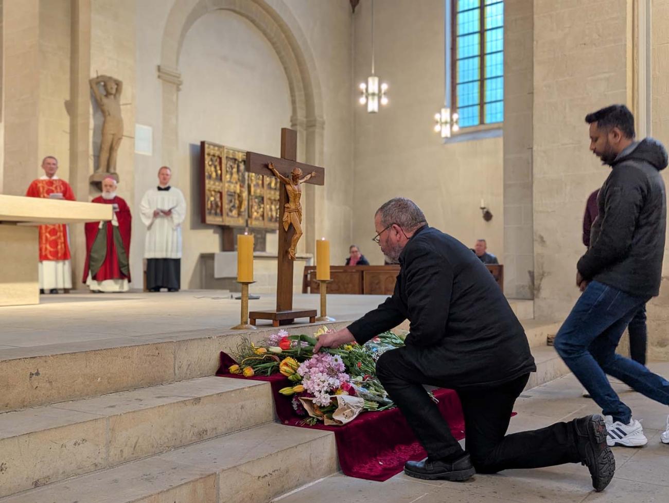 Menschen verneigen sich vor dem Kreuz