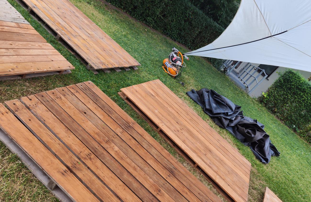Ansicht Floßbau, Holzplatten liegen auf einer Wiese