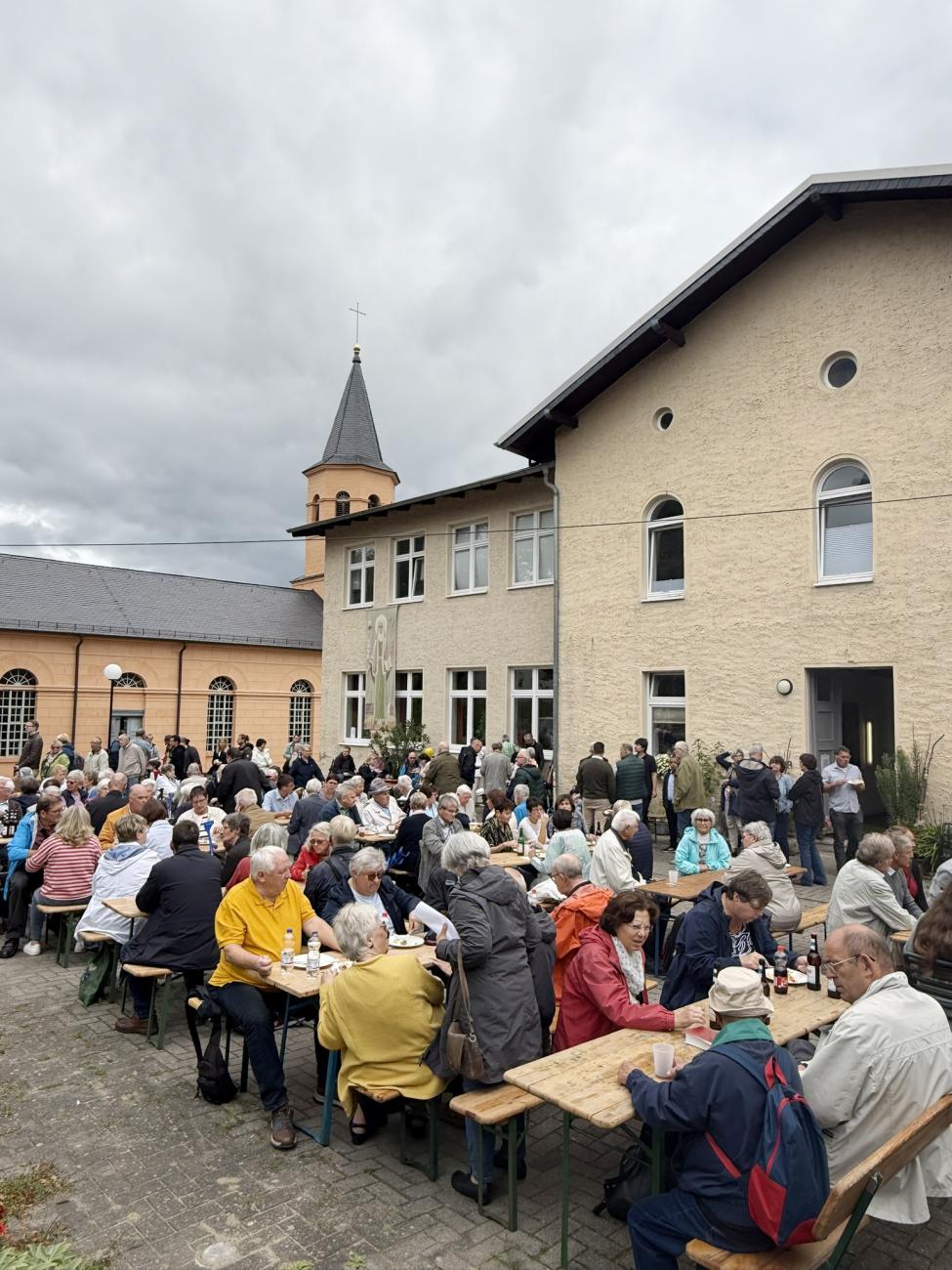 Gläubige sitzen auf Bänken, Essen gemeinsam und tauschen sich aus