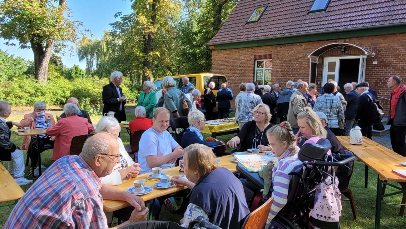 Menschen sitzen an Tischen in einem Garten