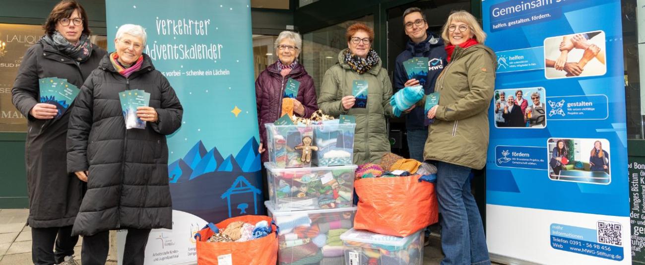 Menschen stehen mit Kisten vor einem Laden