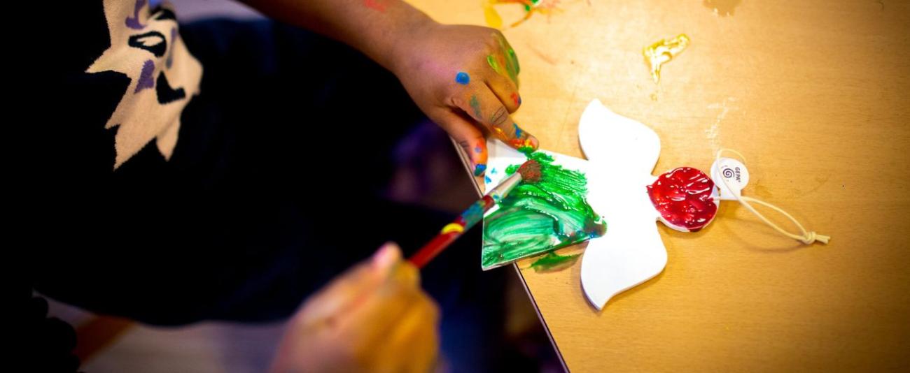 Kinderhände bemalen einen Weihnachtsengel