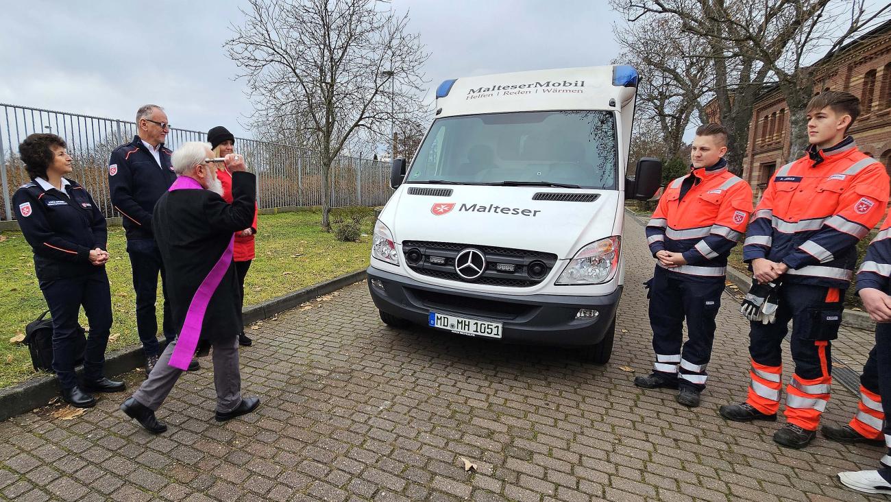 Bischof Fege segnet ein Auto, das Wohnungslosen hilft