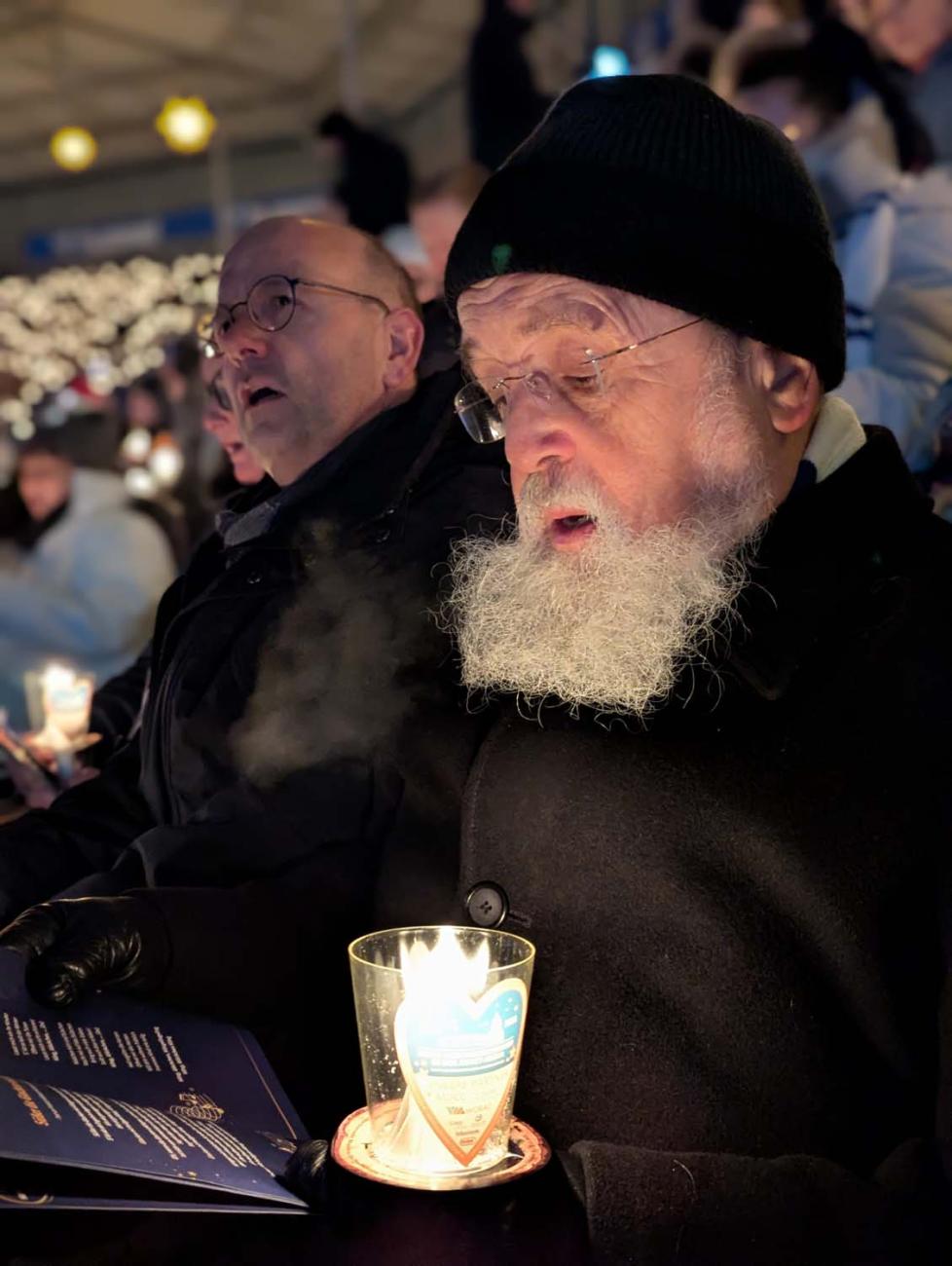 Bischof Feige singt mit einer Kerze in der Hand