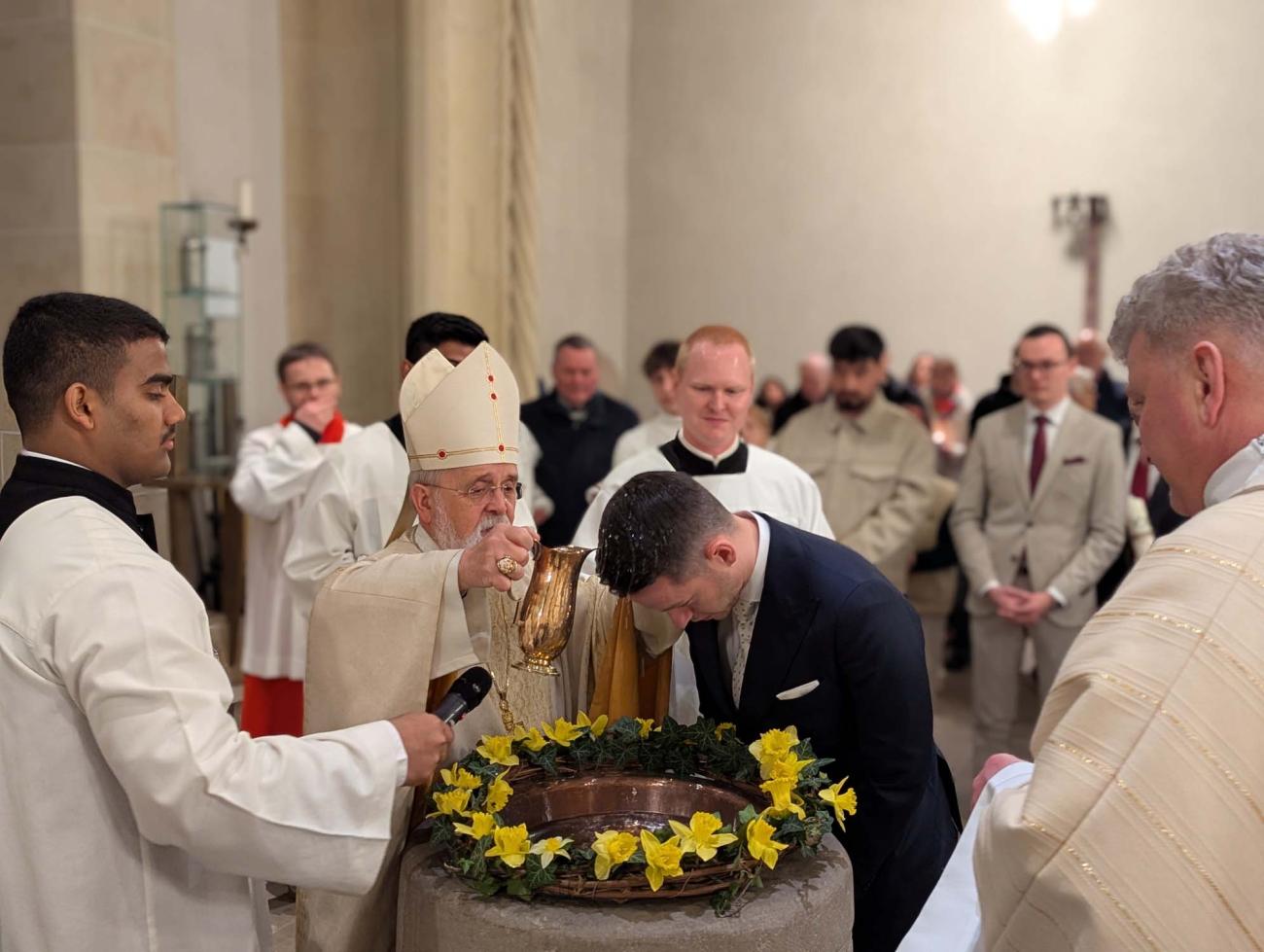 Bischof Feige tauft einen Mann