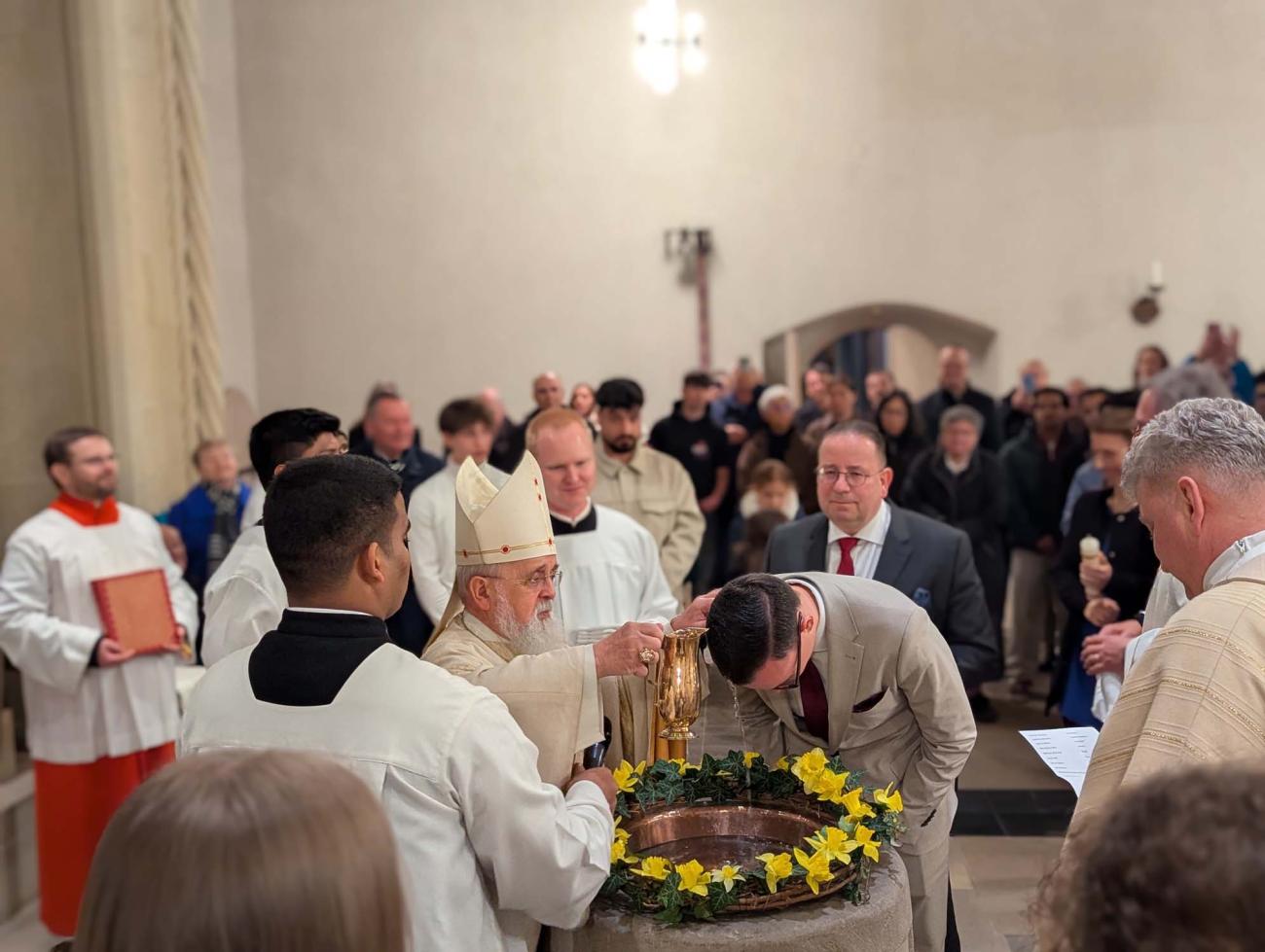 Bischof Feige tauft einen Mann