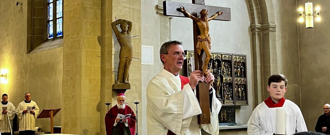 Ein Diakon hält das Kreuz