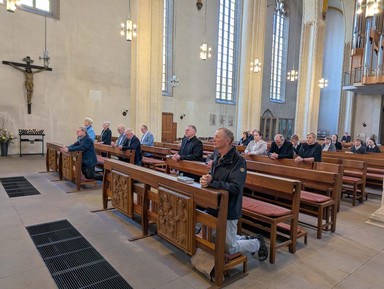 Menschen knien in Kirchenbänken