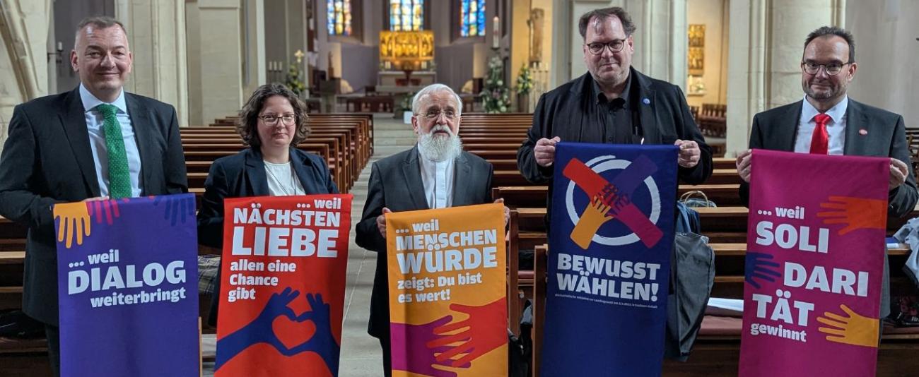 Menschen mit dem Bischof und Bannern in einer Kirche