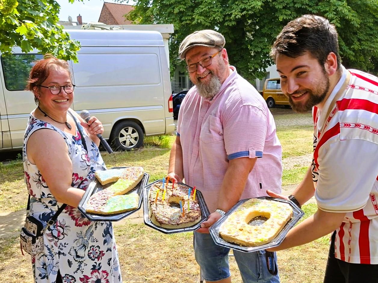 Drei Menschen halten Kuchen
