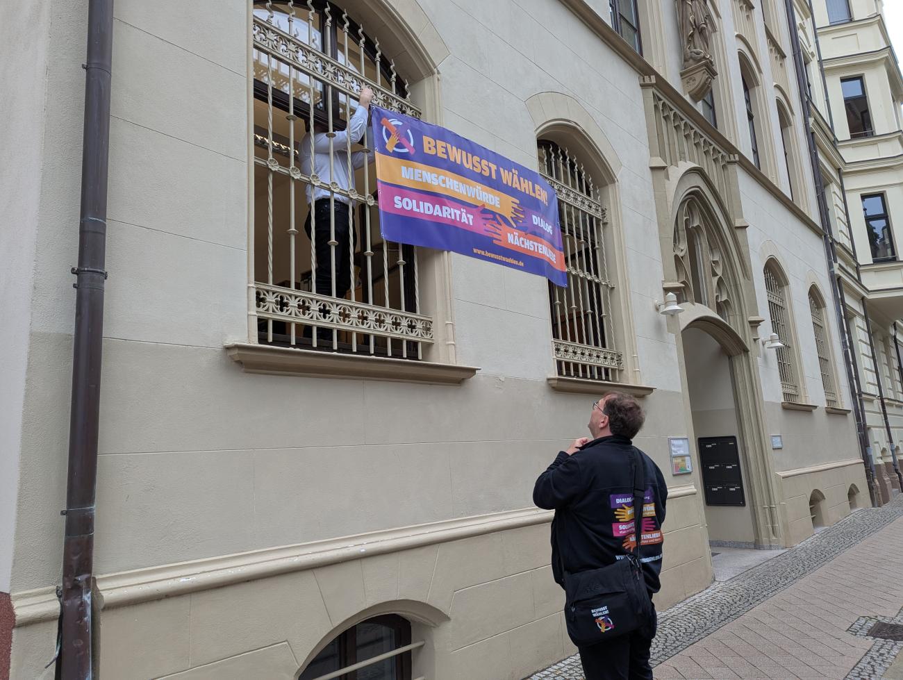 Ein Mann hängt ein Banner auf