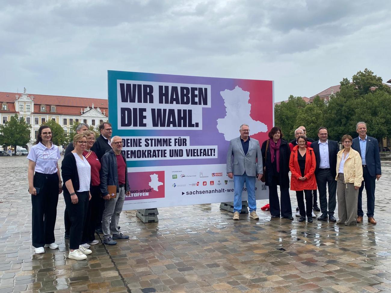 Menschen vor einem Großplakat