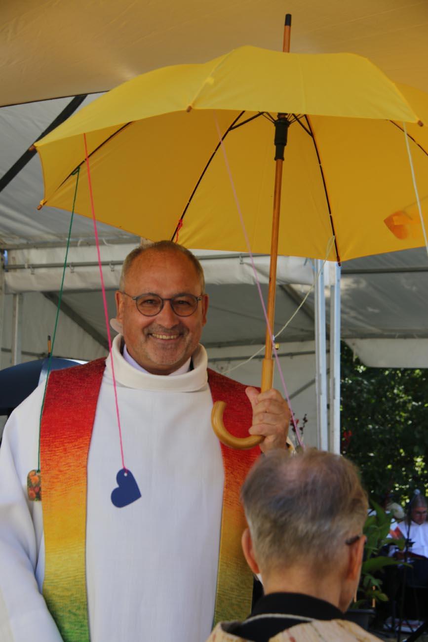 Ein Mann lächelt in die Kamera und hält einen gelben Regenschirm