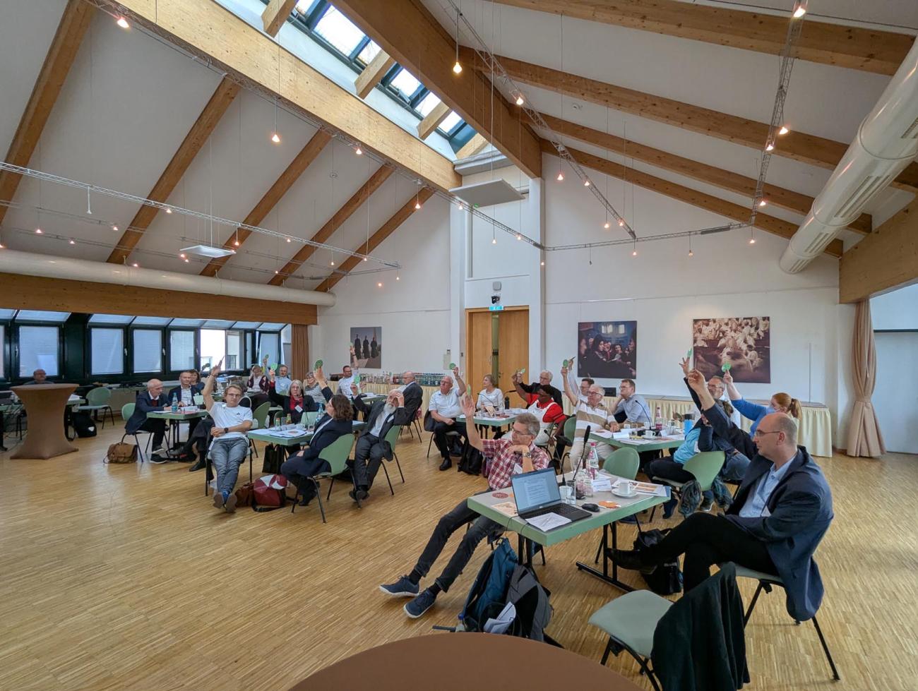 Eine Gruppe Menschen bei einer Abstimmung hebt die Hände