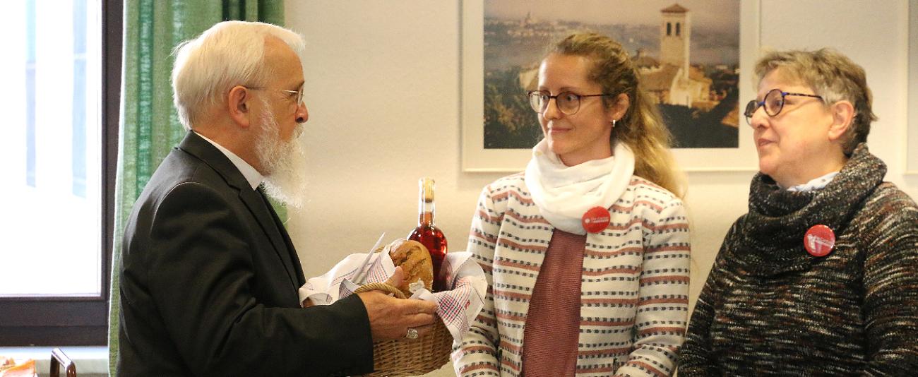 Ein Mann steht mit einem Korb neben zwei Frauen