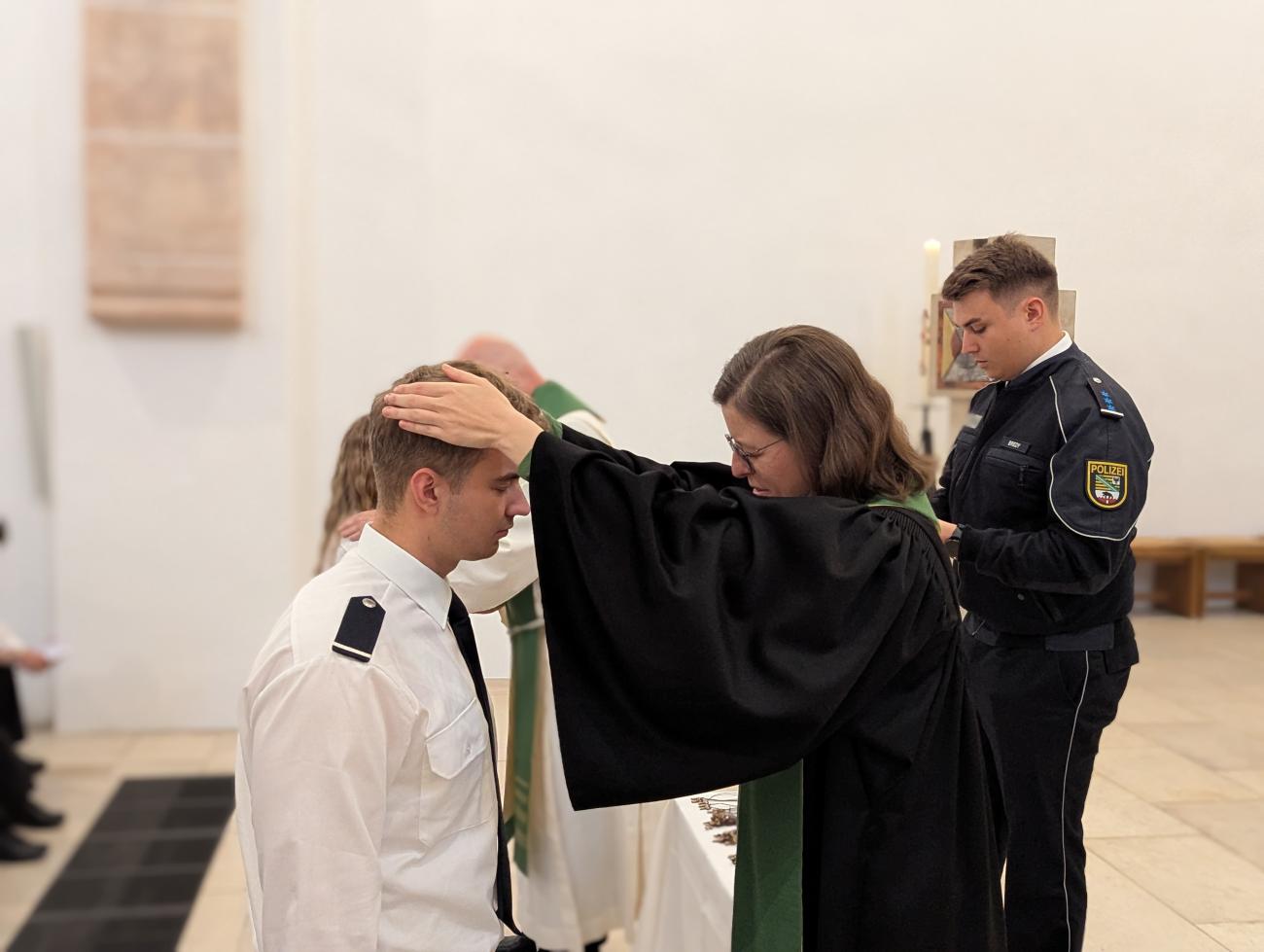 Eine Pfarrerin segnet einen Polizisten