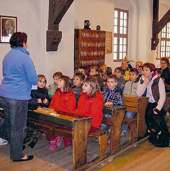 Kinder sitzen in historischem Klassenraum