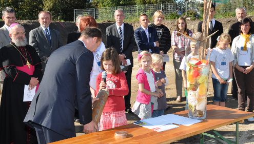 Kinder legen verschiedene Dinge in die Grundsteinschatulle