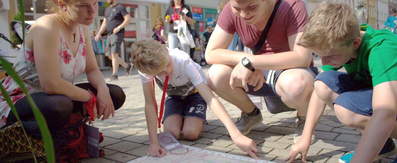 Kinder hocken auf der Straße und schauen auf eine Karte.