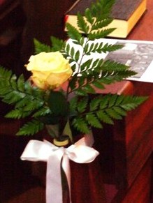 gelbe Blume mit Grün und weißer Schleife
